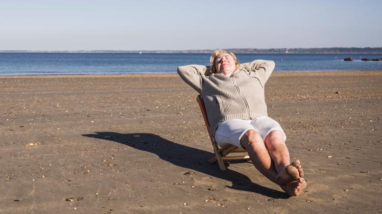 Elderly woman relaxing with hands behind head on deck chair at beach model released, Symbolfoto, UUF28173