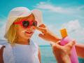 mother put sunblock cream on little daughter face at beach