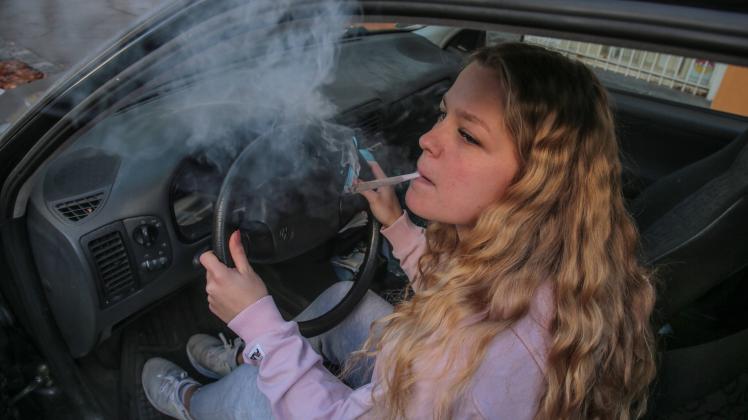 junge frau kifft am autosteuer junge frau kifft am autosteuer *** young woman smokes pot at car steering wheel young wom
