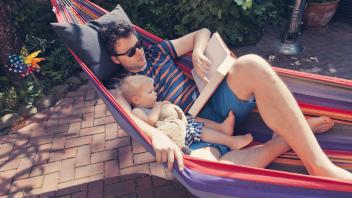 Germany Bonn father and little son looking at a book while in hammock model released property rele