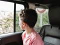 Kid with lollipop sitting on back seat of car and looking out window during road trip in nature in weekend, Model releas
