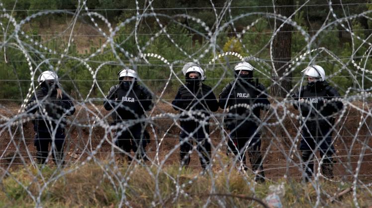 GRODNO REGION, BELARUS - NOVEMBER 22, 2021: Polish police officers are seen behind a barbed wire fence on the Belarusia
