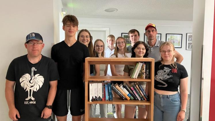 Schüler der elften Klasse haben das Regal mit den ersten Büchern bestückt und freuen sich gemeinsam mit den Beschäftigten in der Tischlerei der Hagenower Werkstätten über das neue Angebot