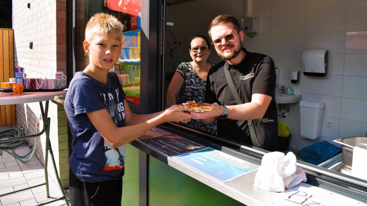 Bippen, Kiosk im Freibad Bippen eröffnet; Ein frisches Stück Pizza serviert Vincenzo Siciliani neben seiner Mutter Helene Siciliani, Kai Schillingmann wird’s schmecken. Foto: Liesel Hoevermann