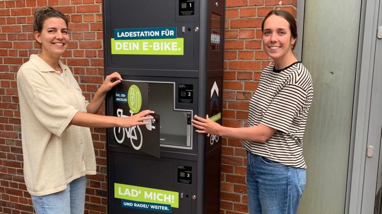 Eva Weusthof, Citymanagerin und Nane Langius, Rad- und Fußverkehrsbeauftragte, präsentieren eine der vier neuen E-Bike Ladestationen in Meppens Innenstadt.