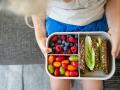Hands of girl holding lunch box with healthy food on sofa at home model released, Symbolfoto property released, SVKF0100
