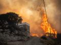 TOPSHOT - A photo shows a fire as it burns vegetation into the village of Gennadi on the Greek Aegean island of Rhodes, on July 25, 2023. Wildfires have been raging in Greece amid scorching temperatures, forcing mass evacuations in several tourist spots including on the islands of Rhodes and Corfu. (Photo by Angelos Tzortzinis / AFP)