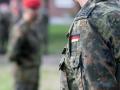 Soldat mit Feldbluse in Flecktarn mit dem Hoheitszeichen der Bundesrepublik Deutschland vor seinem Z