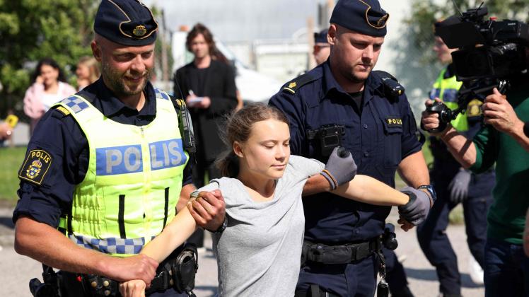 TOPSHOT - Climate activist Greta Thunberg is carried away by police officers after she took part in a new climate action in Oljehamnen in Malmo, Sweden on July 24, 2023, shortly after the city's district court convicted and sentenced her to a fine for disobeying police at a rally last month during a climate action in the Norra hamnen neighbourhood of Malmo. Thunberg was fined on Monday for disobeying police at a rally last month, but said she acted out of necessity due to the climate crisis. (Photo by Andreas HILLERGREN / TT News Agency / AFP) / Sweden OUT