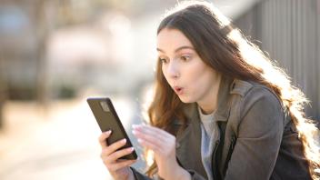 Surprised woman looking at her phone, Surprised woman looking at her phone in the street, Surprised woman looking at her