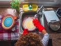 Curly haired woman cleaning dishes at home model released Symbolfoto property released SIPF02382