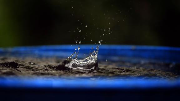 Regen plätschert in eine blaue Regentonne Regen plätschert in eine blaue Regentonne