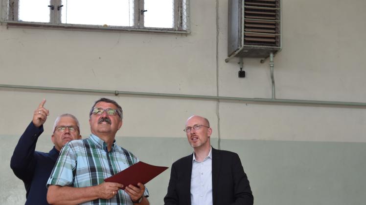 Bürgermeister Lutz Ritter und Amtsvorsteher Eckhard Krüger zeigen Bauminister Christian Pegel  die veralterte Technik in der Sporthalle der Schule Warnow.