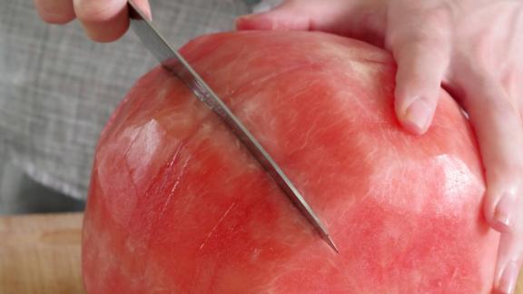 Eine schalenlose Wassermelone wird zerteilt Eine schalenlose Wassermelone wird zerteilt