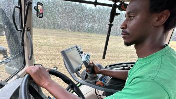 Abduoulaye-Tely Diallo sitzt in einem grünen T-Shirt in einem Landwirtschaftlichen Fahrzeug