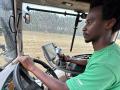 Abduoulaye-Tely Diallo sitzt in einem grünen T-Shirt in einem Landwirtschaftlichen Fahrzeug