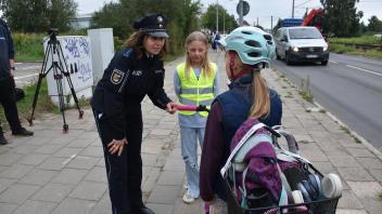 Gemeinsam mit der neunjährigen Aylin (Mitte) klärt Polizeihauptmeisterin Jeannette Damrath-Rekowsky eine kleine Radfahrerin auf, dass sie ihr Rad auf dem Abschnitt zwischen Ampel und Schule eigentlich schieben müsste.