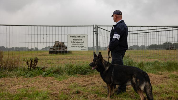 Wachmann mit einem Hund vor dem sogenannten Panzerfriedhof