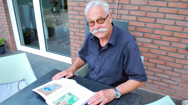 Hobbyhistoriker Dieter Nordholt sitzt mit einem Kunstbuch vor sich am Gartentisch