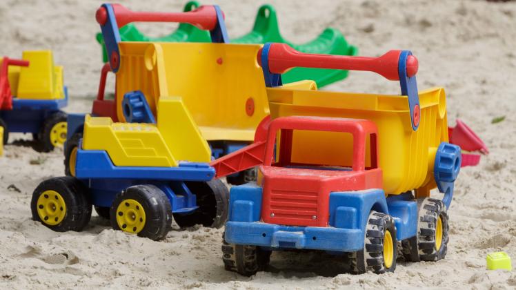 Kinderspielzeug liegt auf einem Spielplatz in einer Sandkiste.