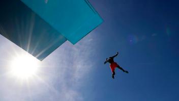 Im Kölner Stadionbad genießen Badegäste den Beginn der Freibad-Saison und springen vom Sprungturm (7,5m) ins Sprungbecke