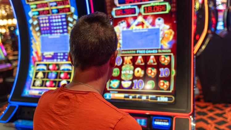 20 July 2023: A young man plays a slot machine in a casino. Symbol image gambling *** Ein junger Mann spielt an einem Sp