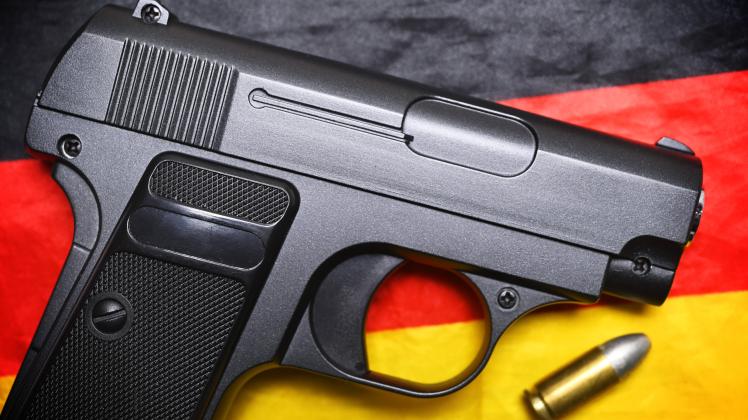 Waffe mit Patrone auf einer Deutschlandfahne *** Weapon with cartridge on a Germany flag