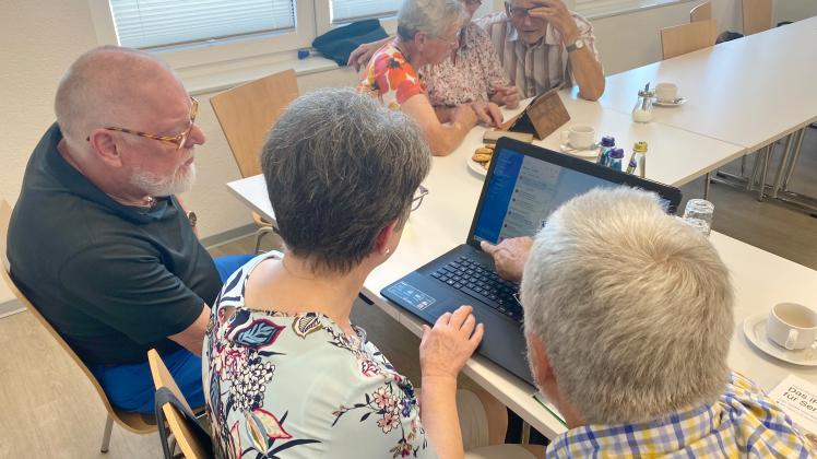 Einige Senioren schauen gemeinsam in einen Laptop.