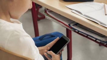 Schoolgirl using a smart phone in classroom, Munich, Bavaria, Germany mit_2017_00280
