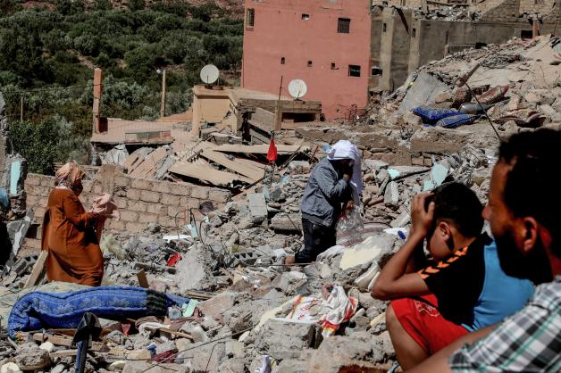 Die Menschen im Erdbebengebiet sitzen vor Trümmern.