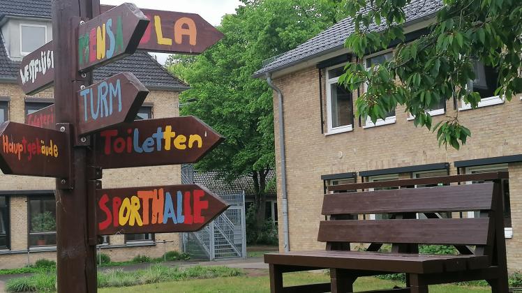 Bank und Hinweisschild auf dem Gelände der Comenius-Gemeinschaftsschule Quickborn