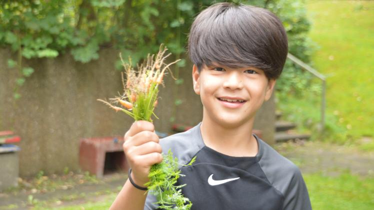 Der zehnjährige Mehran aus der Daz-Klasse der Gorch-Fock-Grundschule Kappeln ist stolz auf sein Bündel selbst geernteter Mini-Karotten.