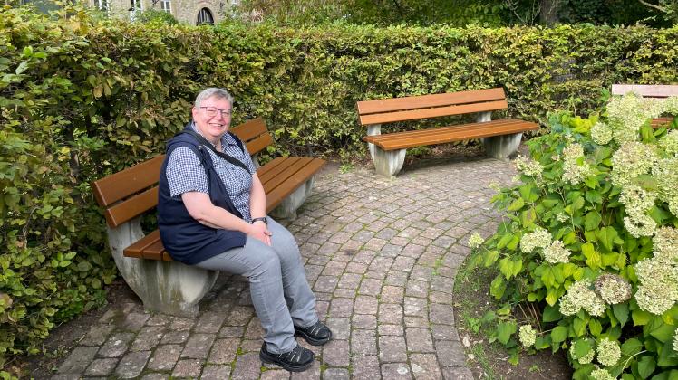 Die Mellerin Annette Schürmann sitzt auf einer Parkbank und lächelt in die Kamera
