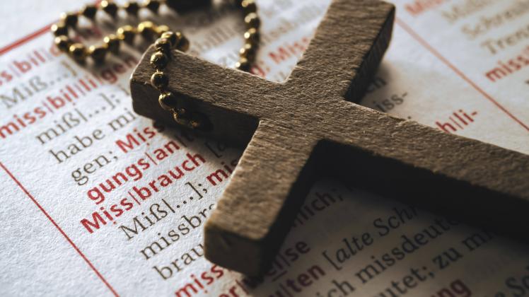 Kreuz auf einem Wörterbuch mit dem Wort Missbrauch, Symbolfoto Missbrauchsskandal