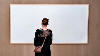 (FILES) A woman stands in front of an empty frame hung up at the Kunsten Museum in Aalborg, Denmark, on September 28, 2021. A Copenhagen court ruled on September 18, 2023 that Danish artist Jens Haaning had to pay 492,549 kroner (66,000 euros) after he had stolen the money that was supposed to be exhibited at Kunsten Museum. The Danish museum loaned the artist $84,000 in cash to recreate old artworks of his using the banknotes, but the boxes he sent only contained blank canvasses and a new title: "Take the Money and Run". (Photo by Henning Bagger / Ritzau Scanpix / AFP) / Denmark OUT / RESTRICTED TO EDITORIAL USE - MANDATORY MENTION OF THE ARTIST UPON PUBLICATION - TO ILLUSTRATE THE EVENT AS SPECIFIED IN THE CAPTION