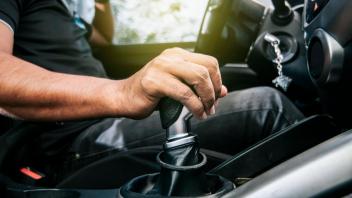 Konzept der Hand, die den Schalthebel eines Autos mit Kopierraum ergreift, Nahaufnahme der Hand des Fahrers am Schaltheb