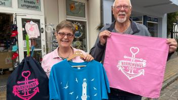 Bevor Bea und Ulrich Sack aus Nordrhein-Westfalen ihre Kreuzfahrtreise auf der „Aidamar“ antreten, decken sie sich noch mit T-Shirts, Rucksack und Kissenbezug aus dem Drachenladen ein. 