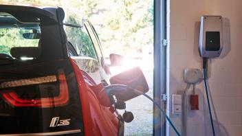 Ein Elektroauto BMW i3 beim Laden an der Wallbox zuhause in der Garage, Lichtreflex E-Auto aufladen *** An electric car