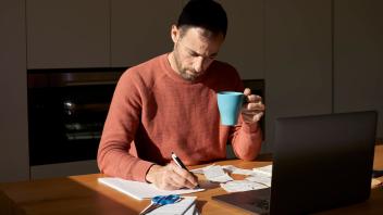 Man with coffee cup writing on paper at desk model released, Symbolfoto property released, VEGF06176