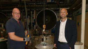 Mirco Krange aus Aschendorf (links) steht zusammen mit dem neuen Geschäftsführer der Opti-Gruppe, Daniel Reeg, in der Färberei im Westrhauderfehner Werk. Dort werden die Reißverschlüsse in einen Farbkessel getaucht. 