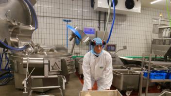 Azubi Phil Graham Schlichter schiebt einen Edelstahlbehälter mit fertiger Wurstmasse vom sogenannten Cutter weg. Für den 17-Jährigen ist die Arbeit bei den Ludwigsluster Fleisch- und Wurstwaren der Traumberuf.