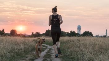Frau joggt auf Feldweg.