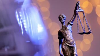 Eine Bronzestatue der Justitia steht auf einem Tisch. Justitia stand in der römischen Mythologie für die ausgleichende G