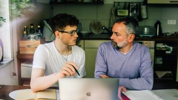 Ein Student sitzt mit seinem Vater vor einem Notebook