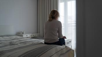 Mature woman sitting alone in the room, sad depressed person. Back view. mental health Mature woman sitting alone in the