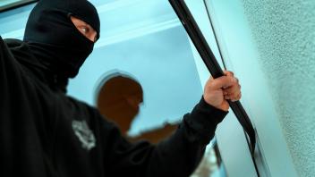 21.11.2022, Thema Einbruchdiebstahl in Wohnhäuser, Symbolbild, Einbrecher versucht durchs Fenster in eine Wohnung zu kom