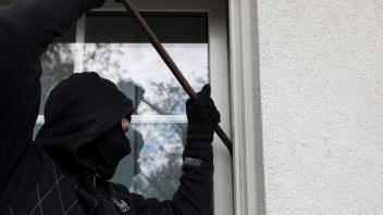 Eine vermummte Person mit einem Brecheisen