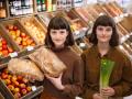 Smiling twin sisters wearing brown shirts holding groceries at farmer s market model released, Symbolfoto property relea