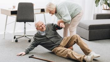 old woman helping to stand up husband who falled down on floor