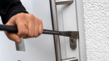 21.11.2022, Thema Einbruchdiebstahl in Wohnhäuser, Symbolbild, Einbrecher versucht mit Brecheisen die Haustüre aufzubrec